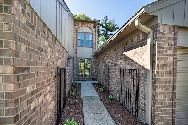 view of side of property featuring board and batten siding, brick siding, and fence