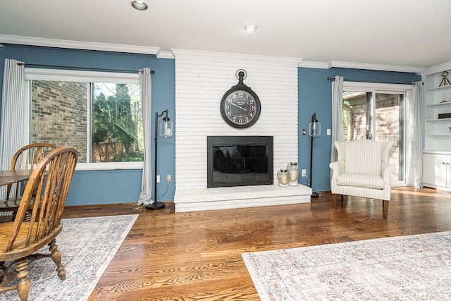 living area with ornamental molding, wood finished floors, and a fireplace