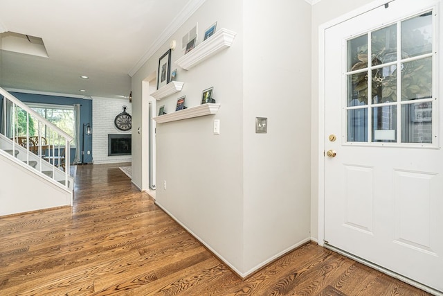 interior space with crown molding, wood finished floors, a fireplace, stairway, and recessed lighting