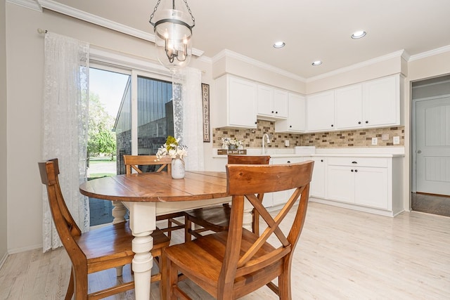 dining space featuring recessed lighting, light wood finished floors, crown molding, and baseboards
