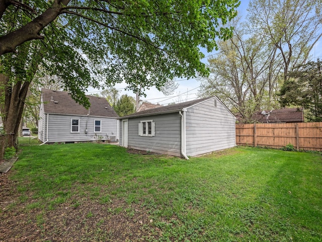 back of property with a lawn, an outbuilding, and a fenced backyard