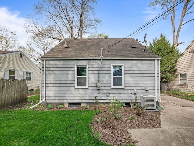 back of house with fence, central AC unit, a yard, and roof with shingles