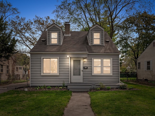 new england style home featuring a chimney and a front lawn