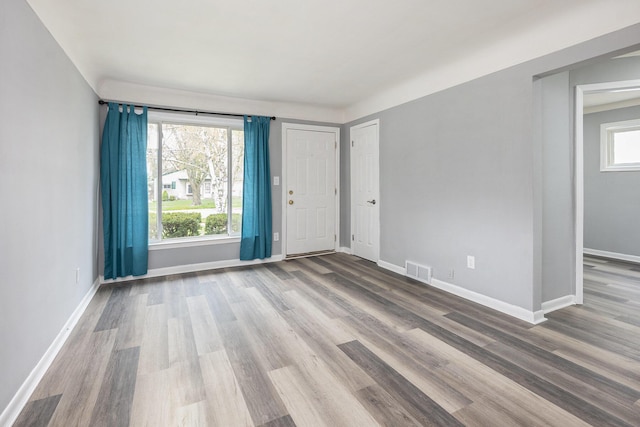 unfurnished room with a healthy amount of sunlight, wood finished floors, and visible vents