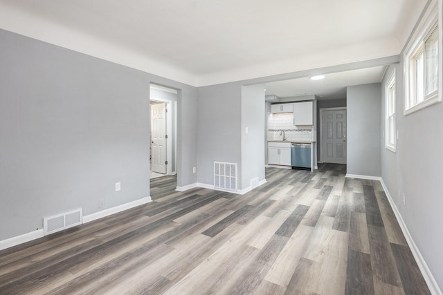 unfurnished living room featuring baseboards, visible vents, and wood finished floors