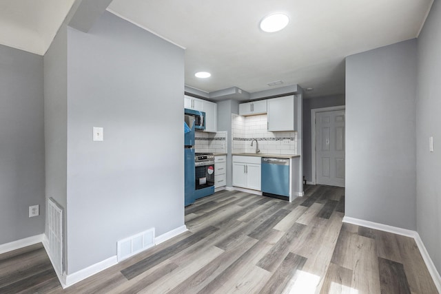 kitchen featuring visible vents, wood finished floors, white cabinets, backsplash, and stainless steel appliances