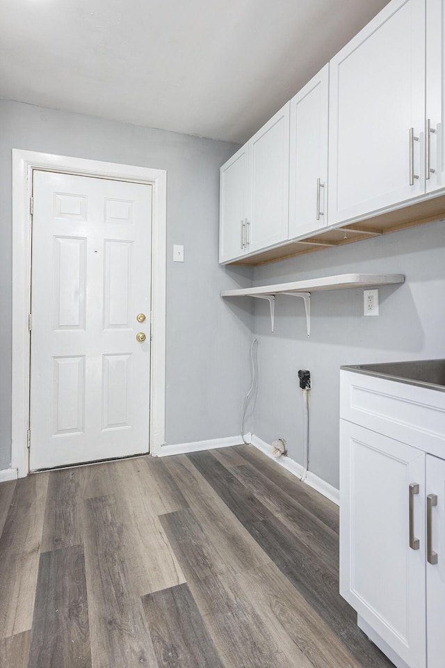 laundry room featuring cabinet space, dark wood-style flooring, and baseboards