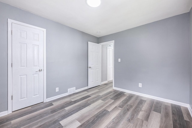 unfurnished bedroom with visible vents, baseboards, and wood finished floors