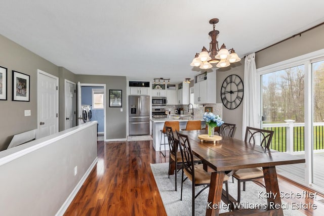 dining room featuring baseboards, dark wood-style flooring, washing machine and dryer, and a chandelier