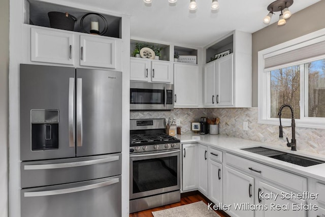 kitchen with backsplash, appliances with stainless steel finishes, a sink, light countertops, and white cabinetry