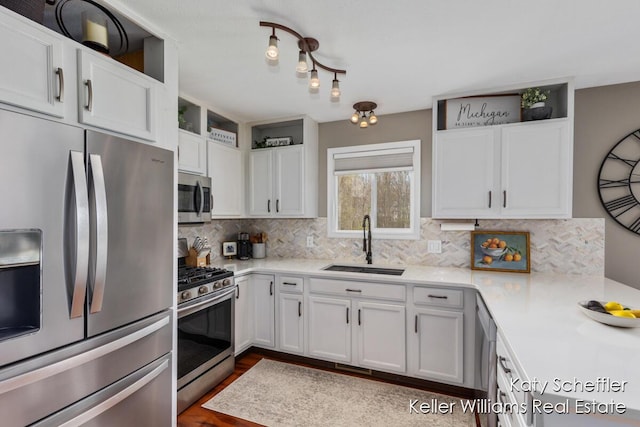 kitchen with light countertops, stainless steel appliances, white cabinets, and a sink