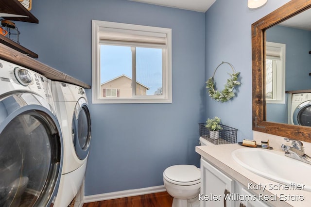 half bathroom featuring independent washer and dryer, vanity, toilet, baseboards, and wood finished floors