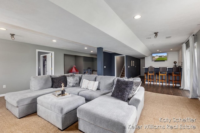 carpeted living area with recessed lighting, bar, baseboards, and stairway