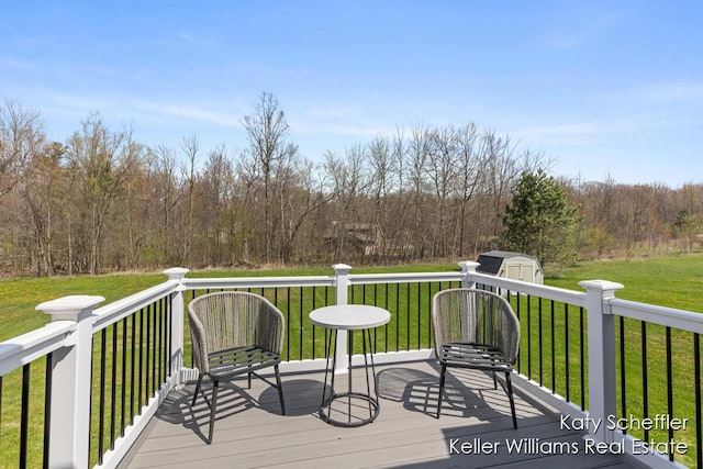 deck with an outdoor structure, a shed, a yard, and a wooded view