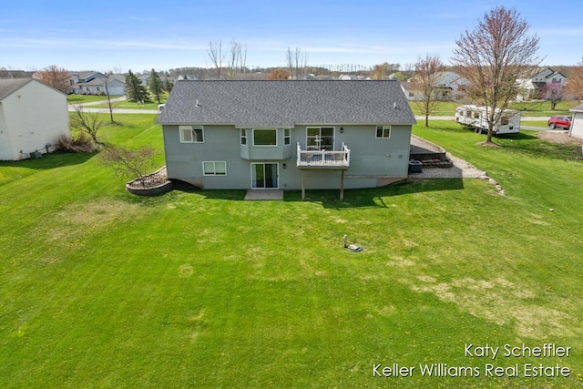 back of property with roof with shingles, a yard, and a residential view