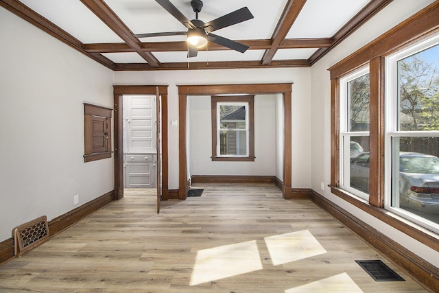 unfurnished room featuring visible vents, coffered ceiling, and a wealth of natural light
