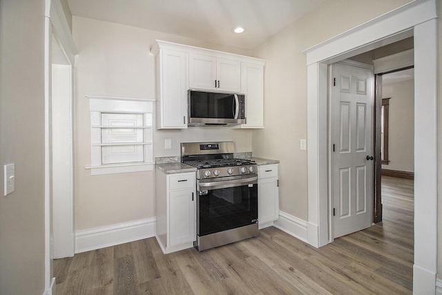 kitchen featuring white cabinetry, baseboards, stainless steel appliances, recessed lighting, and light wood-style flooring