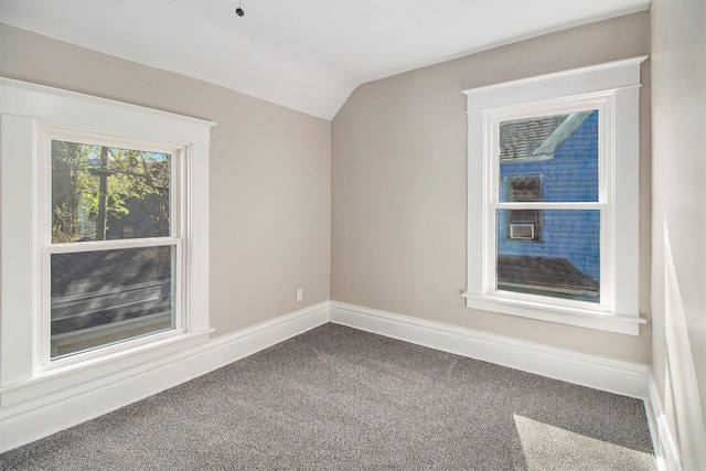 unfurnished room featuring dark colored carpet, baseboards, and lofted ceiling