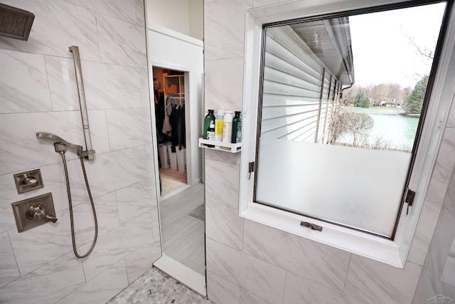 bathroom featuring a walk in closet and a tile shower