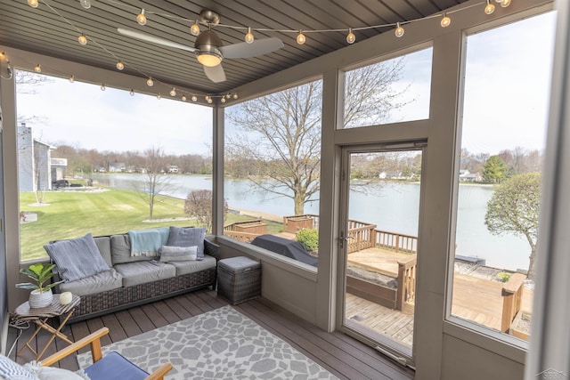 sunroom / solarium featuring a ceiling fan and a water view