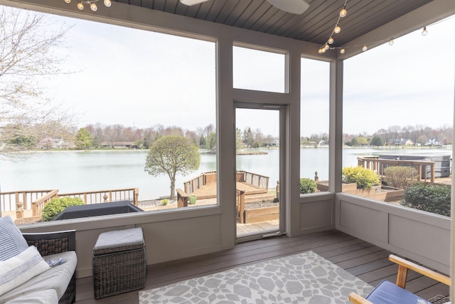 sunroom / solarium featuring plenty of natural light, a ceiling fan, and a water view