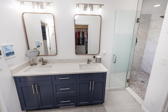 full bath featuring a sink, baseboards, a stall shower, and double vanity