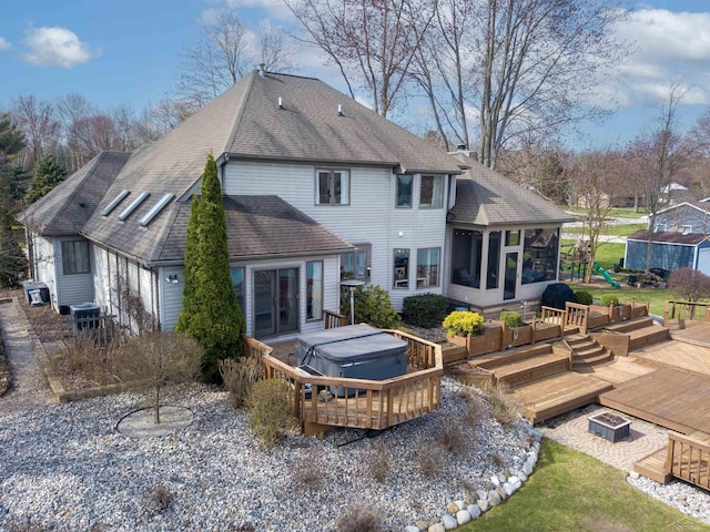 rear view of house with roof with shingles, a hot tub, central AC, a wooden deck, and a sunroom