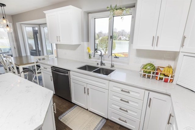 kitchen featuring stainless steel dishwasher, pendant lighting, white cabinets, a sink, and backsplash