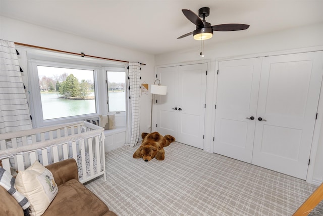 carpeted bedroom featuring a ceiling fan and two closets