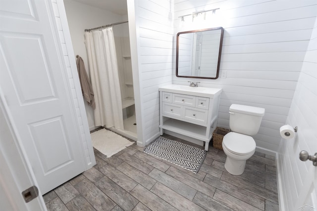 full bathroom with wooden walls, vanity, a stall shower, and toilet