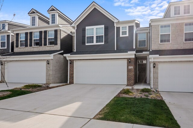 view of property featuring brick siding, a garage, and driveway