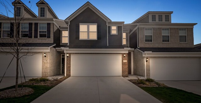 multi unit property with an attached garage, concrete driveway, and brick siding