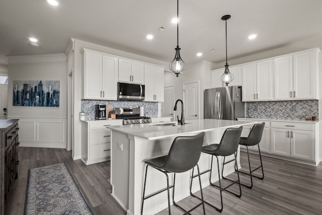 kitchen with a kitchen island with sink, backsplash, a sink, light countertops, and stainless steel appliances