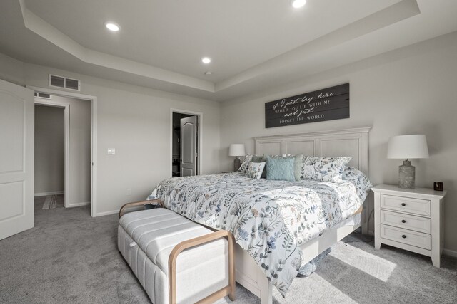 bedroom with carpet flooring, recessed lighting, baseboards, a tray ceiling, and visible vents
