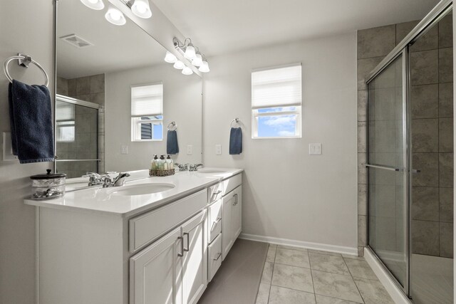 bathroom featuring tiled shower, visible vents, plenty of natural light, and a sink