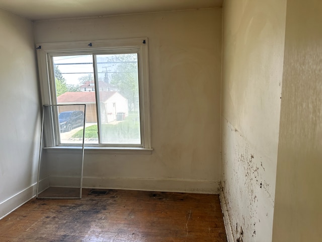 spare room featuring baseboards, wood-type flooring, and visible vents