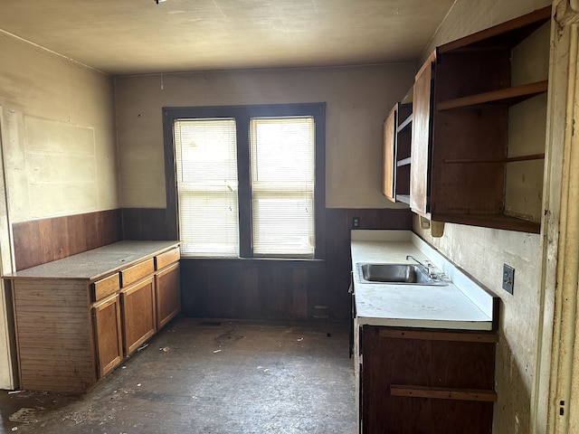 kitchen with light countertops, brown cabinets, open shelves, and a sink