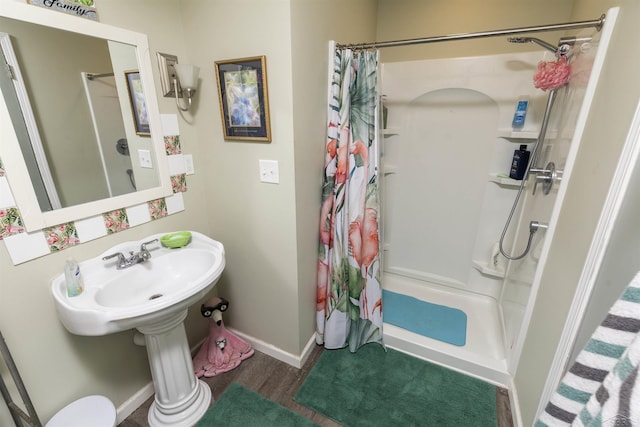 bathroom featuring wood finished floors, baseboards, and a stall shower