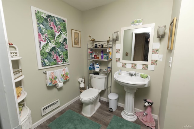 half bathroom featuring toilet, baseboards, wood finished floors, and a baseboard radiator