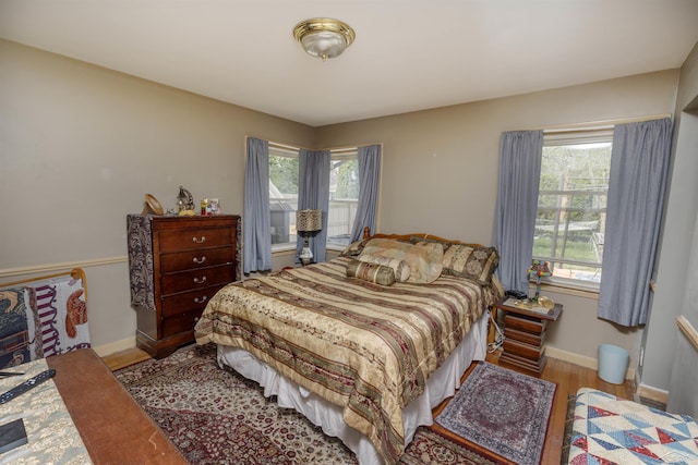 bedroom with baseboards, multiple windows, and wood finished floors