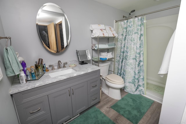 bathroom with toilet, a shower with curtain, wood finished floors, and vanity