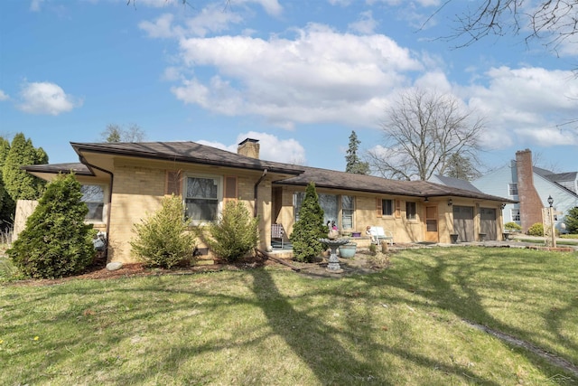 rear view of house with a garage, a chimney, a yard, and brick siding