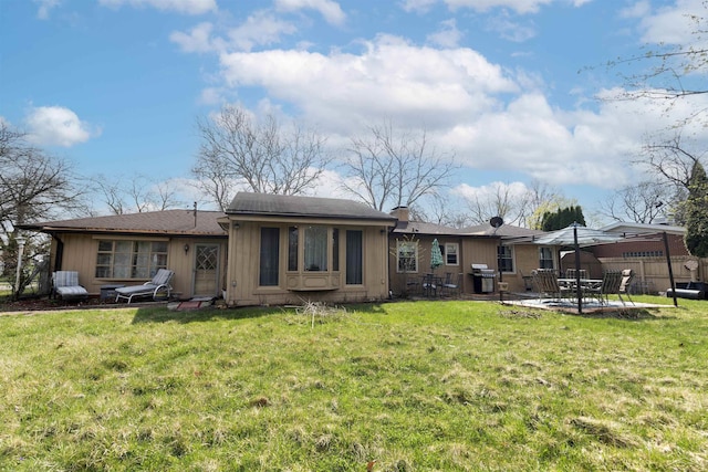 rear view of property featuring a lawn, a patio, and fence