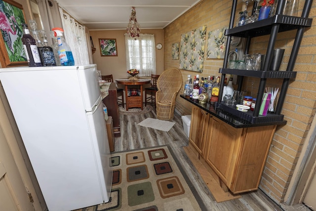 interior space with freestanding refrigerator, light wood-type flooring, and a bar