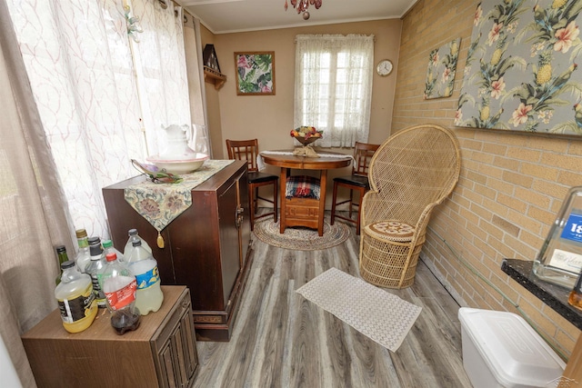 living area with crown molding, wood finished floors, and brick wall