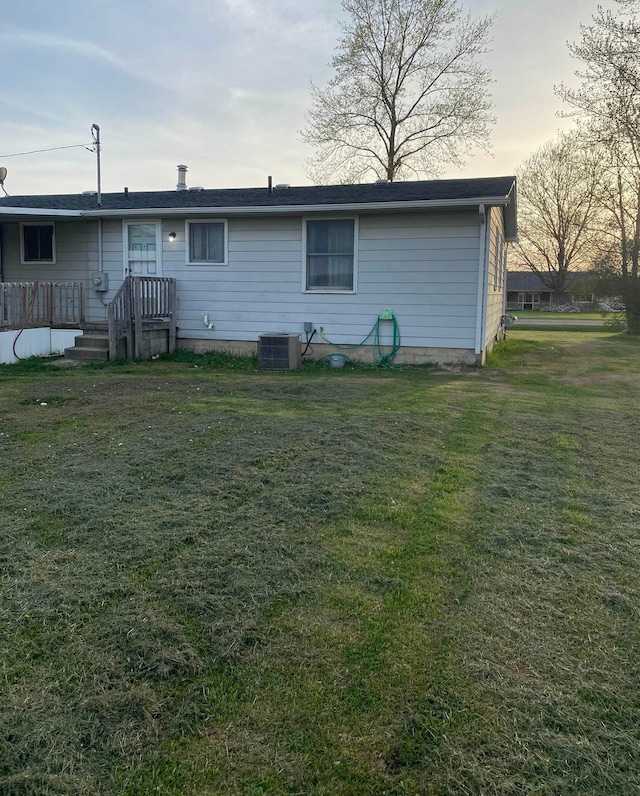 back of house with central AC and a yard