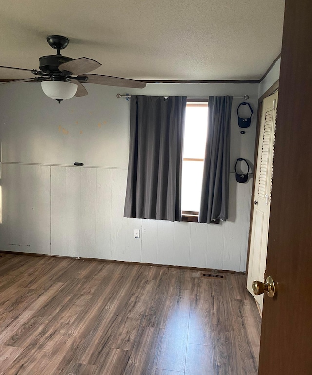 spare room featuring a ceiling fan, a textured ceiling, visible vents, and wood finished floors