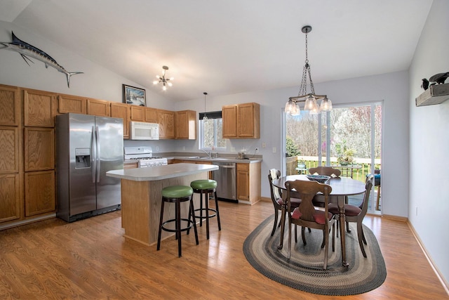 1077 Sun Valley Ln, Allegan, MI 49010 - kitchen featuring a kitchen bar, a center island, light wood-style flooring, a notable chandelier, and stainless steel appliances