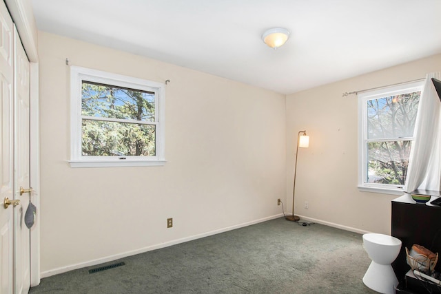 unfurnished bedroom featuring carpet floors, baseboards, visible vents, and multiple windows