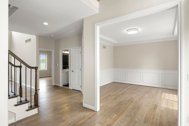 entrance foyer with visible vents, crown molding, wood finished floors, and stairway